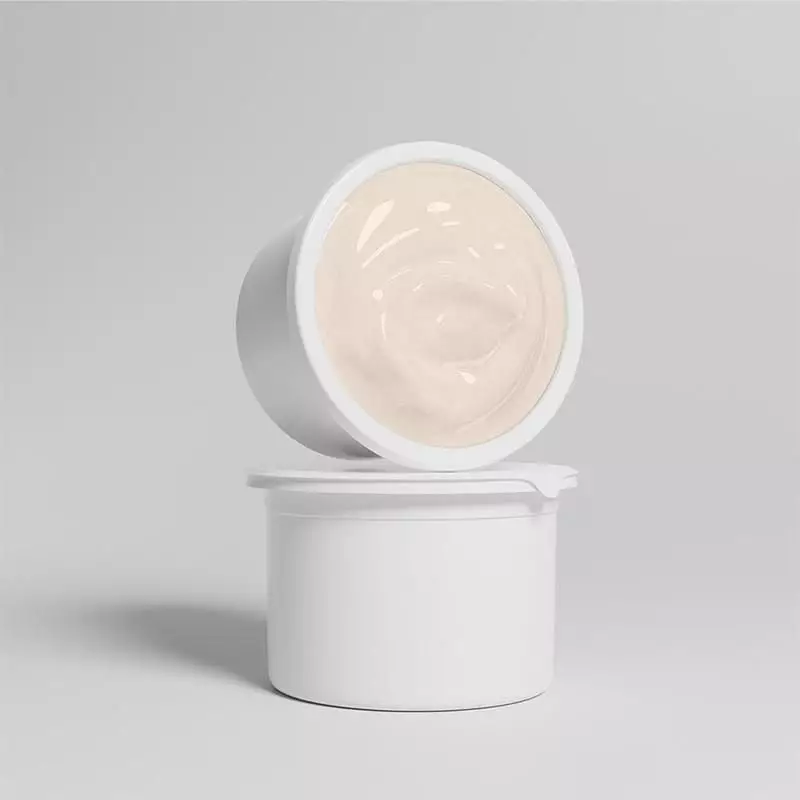 Gros plan sur la recharge ouverte STIM RENEW 15 révélant la texture crémeuse beige dans le contenant