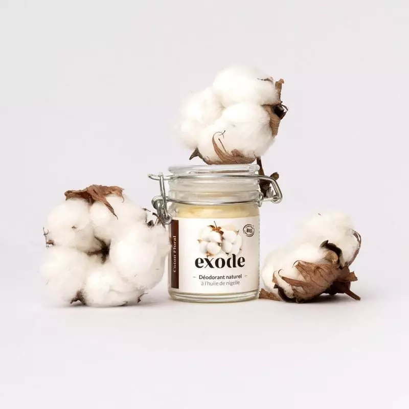 Baume déodorant bio Exode 1454427 posé sur une étagère de salle de bain avec des fleurs de coton.