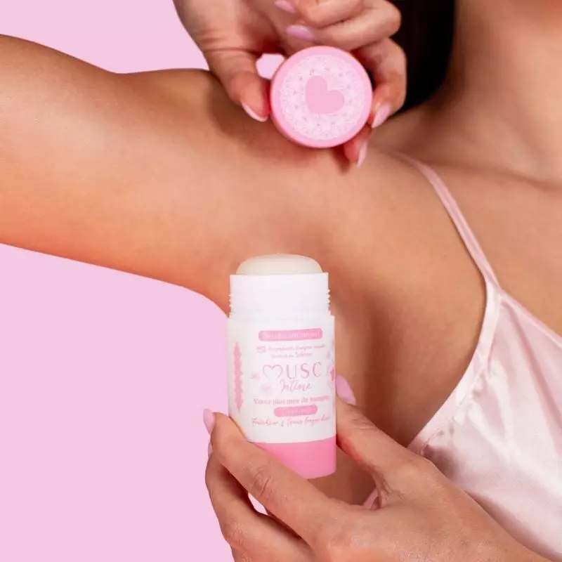 Photo lifestyle d'une femme appliquant le déodorant solide Musc Intime, souriant, profitant d'un par