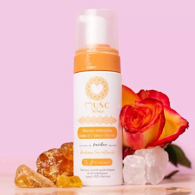 Photo ambiante du produit Musc Intime Mousse Intime Ambre Rose 150ml, flacon pompe rose sur fond flo
