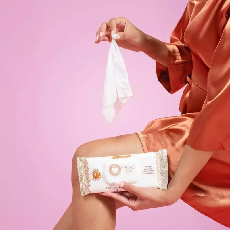 Femme utilisant les lingettes intimes Musc Intime 1987230 lors d'une pause voyage, avec une valise e