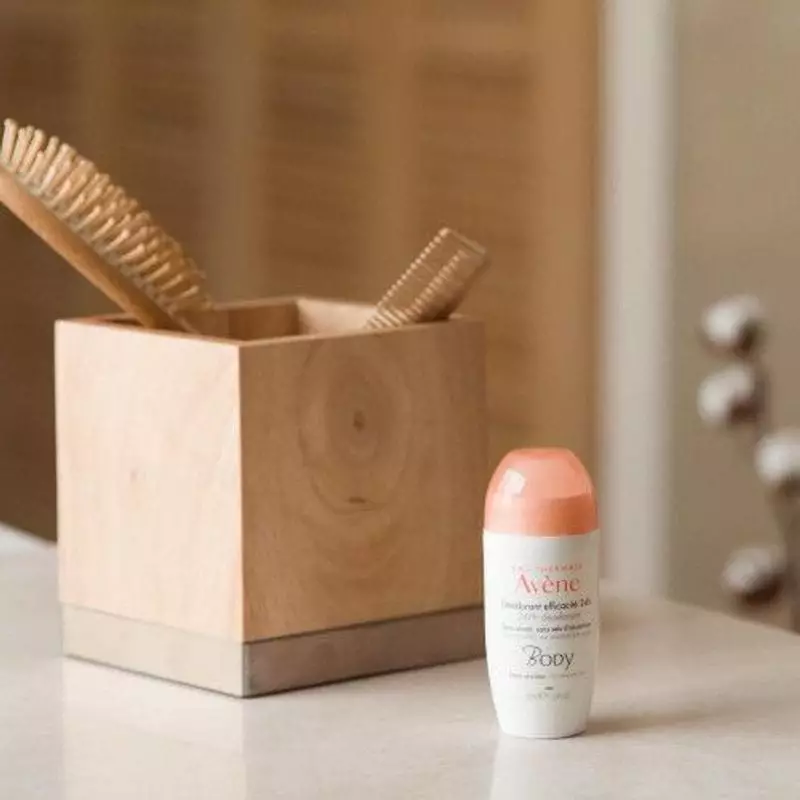 Déodorant Avène 24h posé sur un comptoir de salle de bain à côté d'une serviette et de verdure, créa