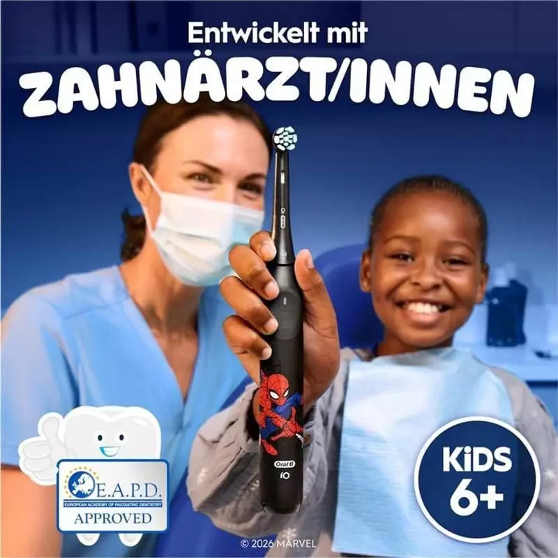 Dentiste en uniforme démontrant la brosse à dents Oral-B iO Kids Spiderman à un enfant patient souri