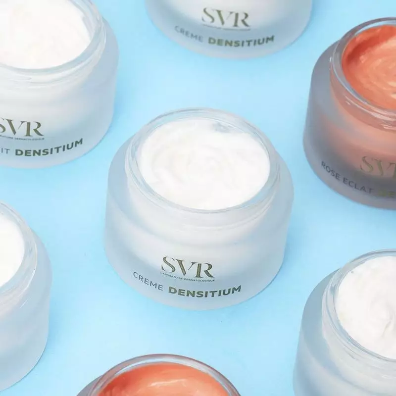 Multiples pots de crème SVR Densitium blancs et variantes comme Rose Éclat sur fond bleu, pots ouver