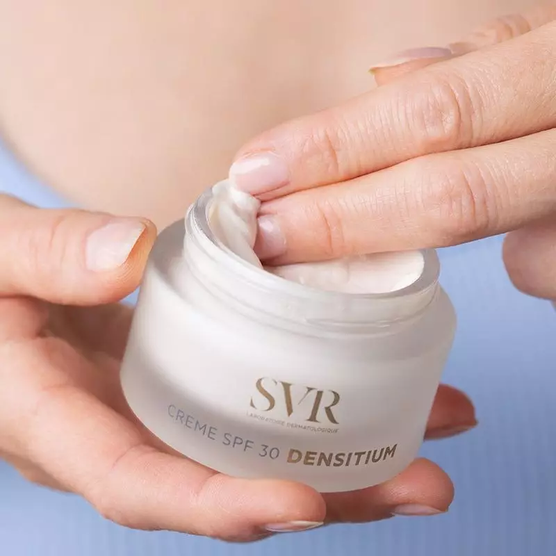Gros plan sur la main d'une femme appliquant la crème SVR Densitium SPF30, pot ouvert avec texture c