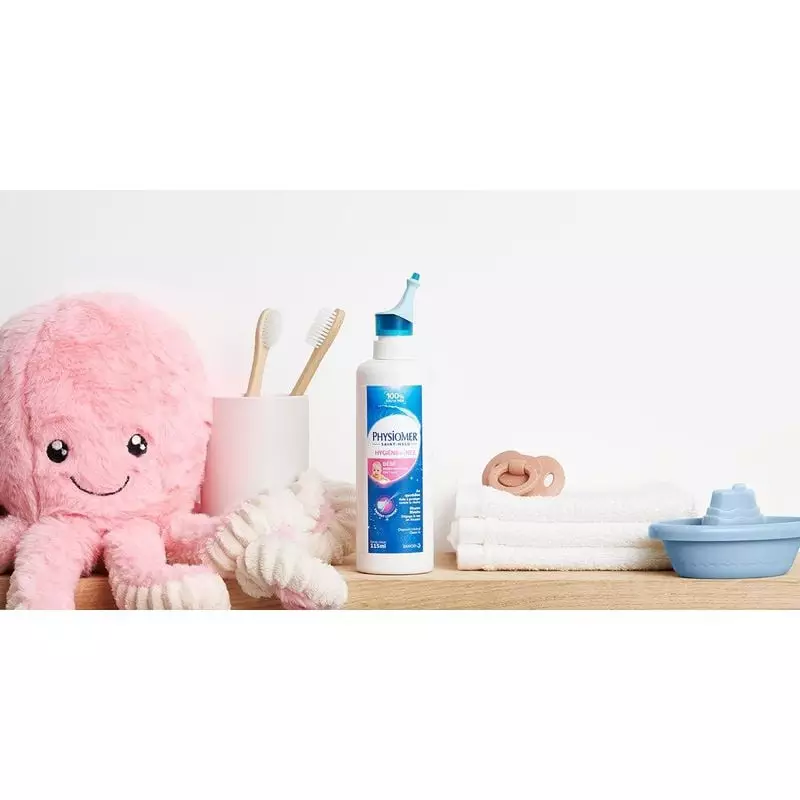 Flacon de spray nasal Physiomer Bébé dans une chambre de bébé avec jouet pieuvre rose, brosse à dent