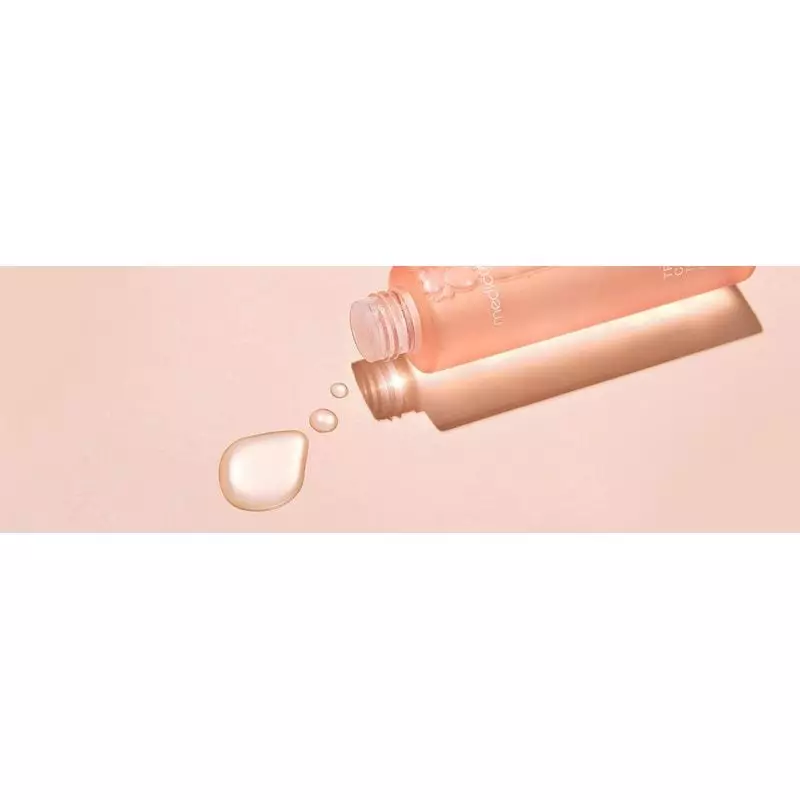 Flacon Medicube Triple Collagen Toner incliné, laissant couler des gouttelettes claires de tonique s