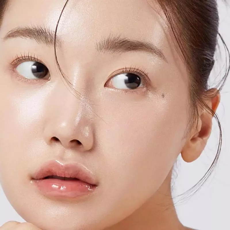 Gros plan sur le visage d'une femme montrant une peau éclatante et hydratée, soulignant les effets d