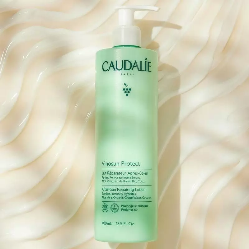Lait réparateur après-soleil Caudalie Vinosun Protect 400 ml en flacon pompe vert clair, posé sur ti