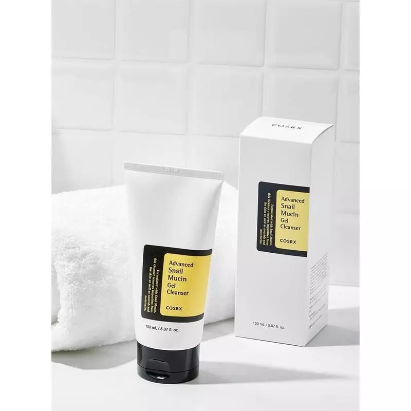 Tube de nettoyant gel COSRX à la mucine d'escargot à côté de sa boîte blanche sur serviette blanche,