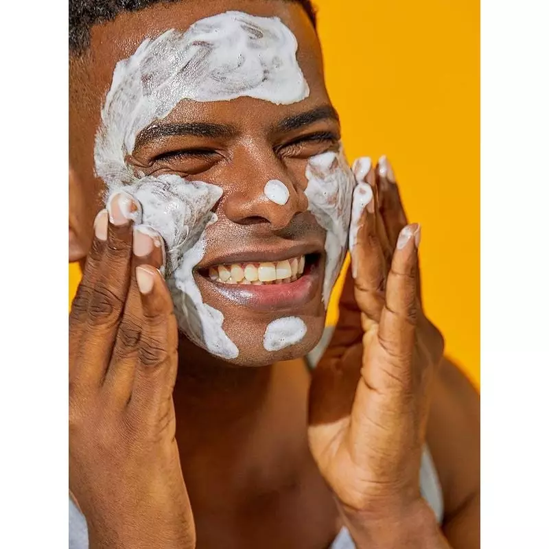 Homme souriant avec une riche mousse blanche du Nettoyant Gel à la Mucine d'Escargot COSRX appliquée