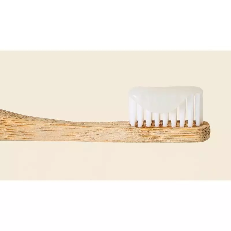 Gros plan sur brosse à dents en bambou avec généreuse noisette de dentifrice menthe What Matters tra