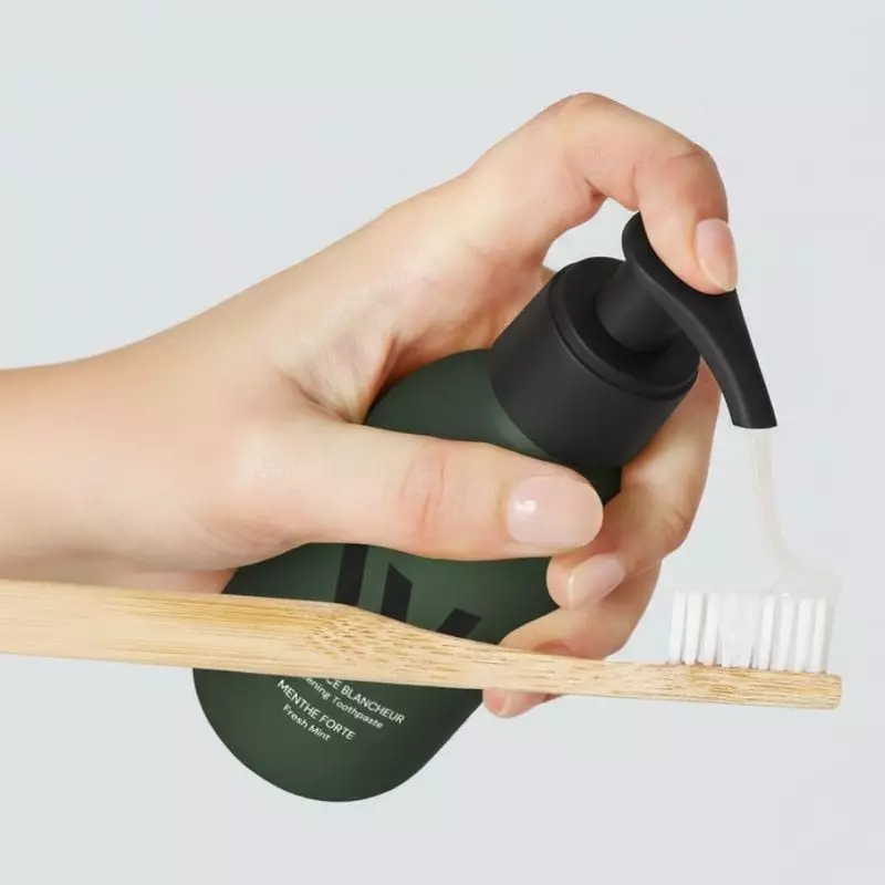 Femme tenant le distributeur de dentifrice blanchissant What Matters 1065123 vert près de son cou, é