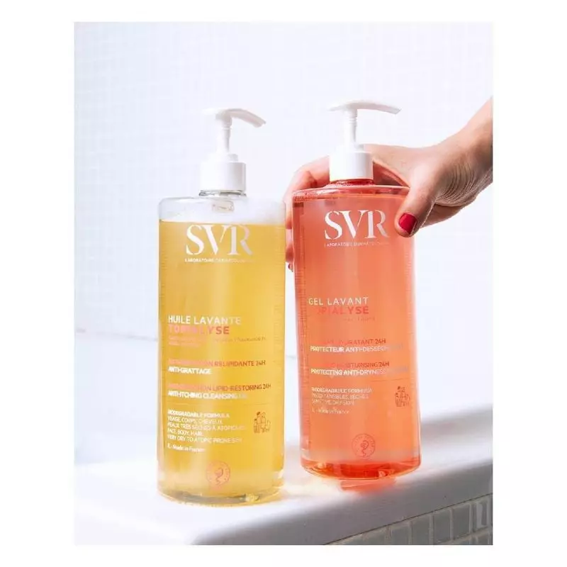 Femme sous la douche souriante, utilisant la pompe SVR Topialyse Huile Lavante pour créer de la mous