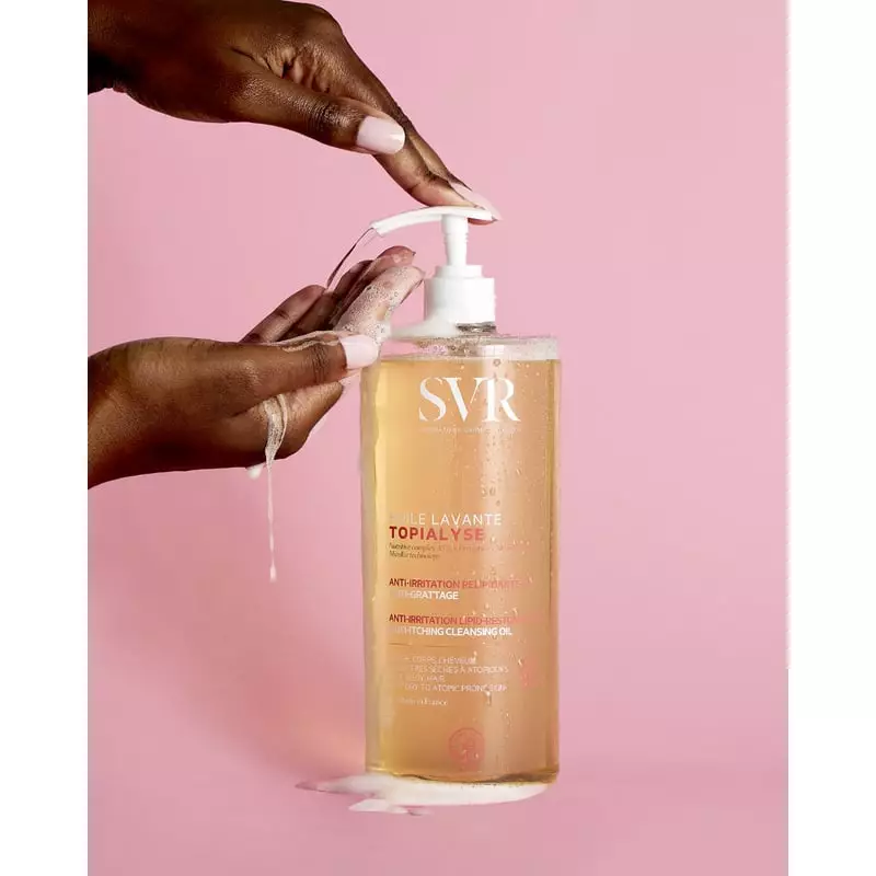 Gros plan sur le flacon SVR Topialyse Huile Lavante avec mains pompant une mousse riche dans la paum