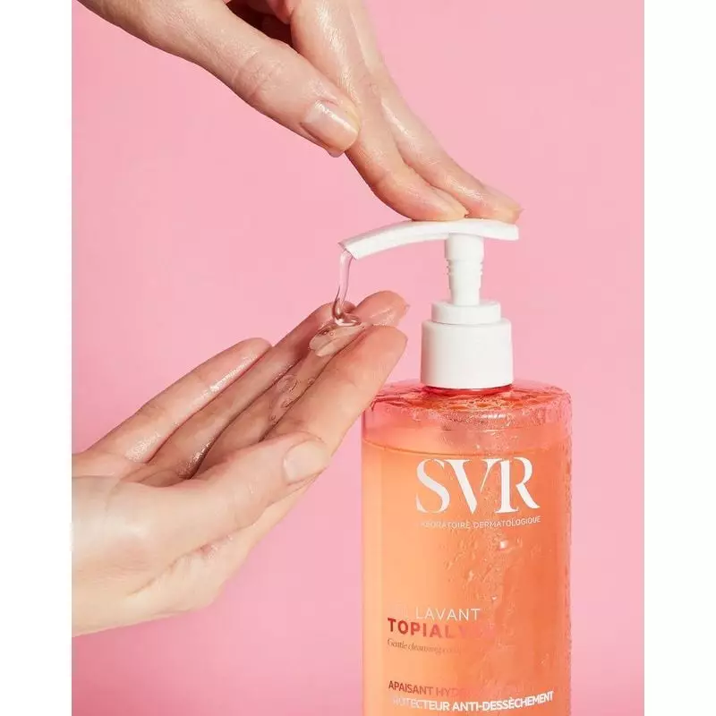 Gros plan d'une main dispensant le gel lavant doux SVR Topialyse clair d'un flacon pompe.