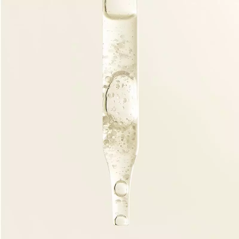 Femme appliquant une goutte de sérum Embryolisse sur sa joue, gros plan sur la peau rayonnante penda