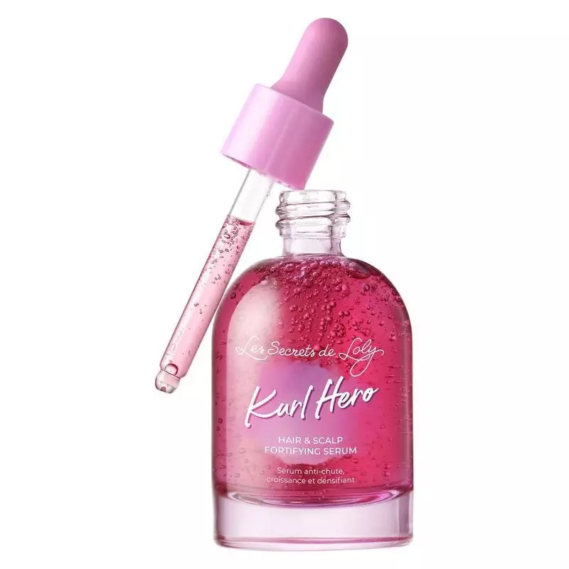 Gros plan sur la pipette rose du sérum Kurl Hero dispensant une goutte de sérum rose du flacon magen