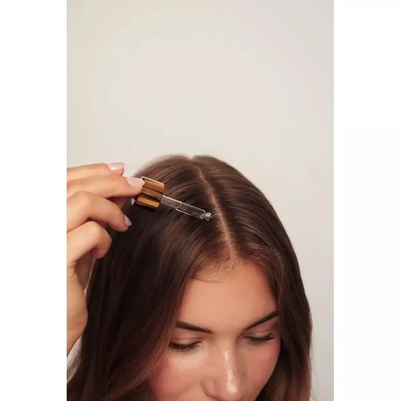 Gros plan du flacon compte-gouttes du sérum capillaire Rosehair, montrant la formule et l'embout d'a