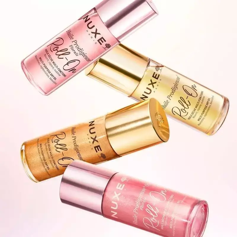 Flacon roll-on Nuxe Prodigieux Florale 60ml posé sur un fond boisé, entouré de pétales de magnolia e