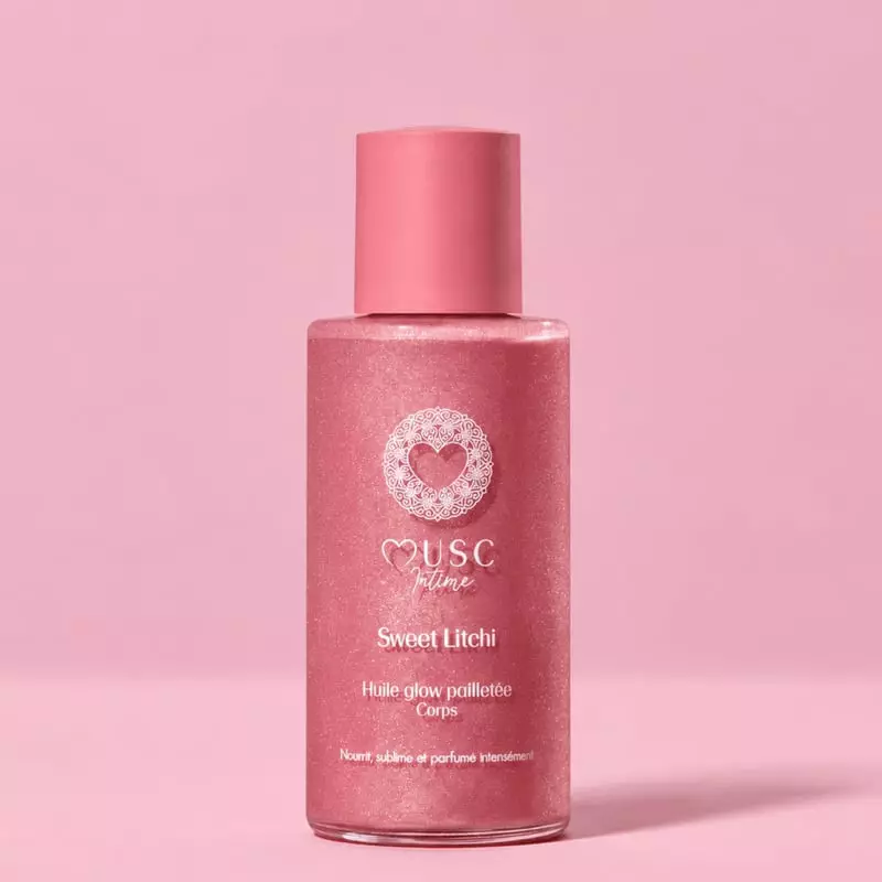 Packshot de l'Huile Glow Pailletée Corps Sweet Litchi de Musc Intime dans un flacon rose avec un bou