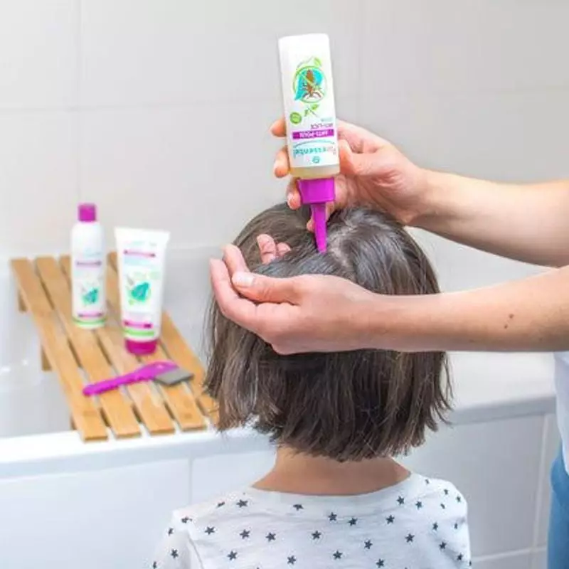 Image lifestyle d'un parent appliquant la lotion anti-poux Puressentiel sur les cheveux d'un enfant 