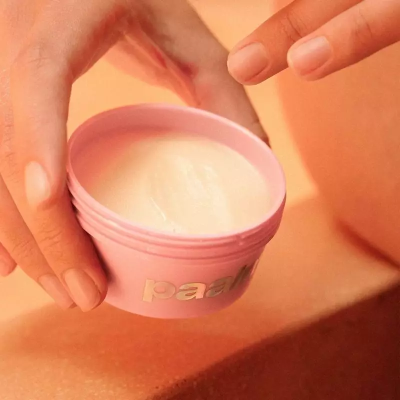 Image lifestyle d'une femme appliquant le baume déodorant Paalm Candy Sweet sur son aisselle, souria
