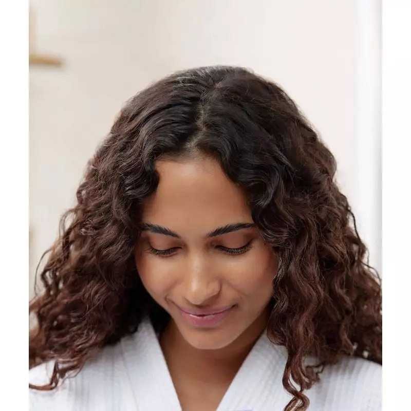 Main versant la recharge de shampoing nourrissant La Rosée dans un flacon en verre