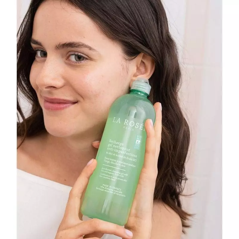 Femme appliquant le gel nettoyant anti-imperfections La Rosée sur son visage dans une salle de bain
