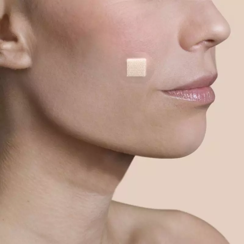 Personne portant un pansement discret de couleur chair pour le visage Urgo Spécial Visage sur la jou