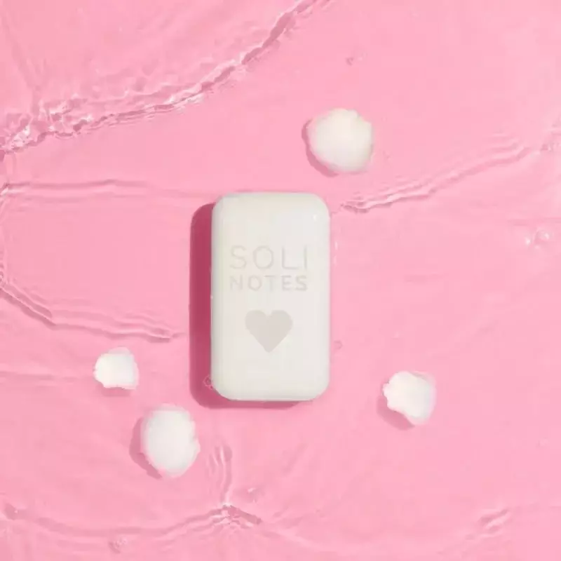 Femme faisant mousser le savon solide à la rose Solinotes 1985896 sous l'eau courante, créant une mo