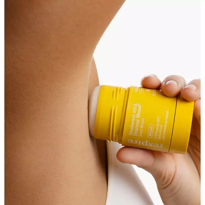Femme appliquant le stick déodorant naturel Respire 1985885 sous le bras dans une salle de bain