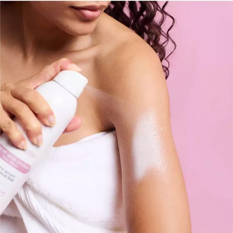 Photo lifestyle d'une femme appliquant le lait corporel Musc Intime 1985872 sur son bras, souriant.