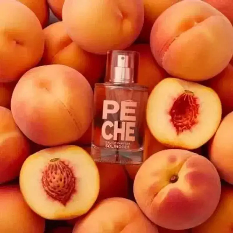 Image d'ambiance du parfum Solinotes Pêche à côté de pêches fraîches sur une table en bois, évoquant