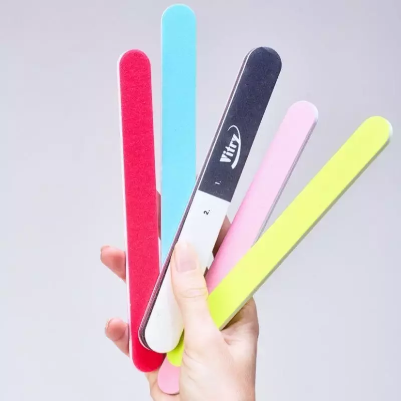 Lime à ongles Vitry 2067651 limant doucement un ongle artificiel, démontrant sa polyvalence et son g