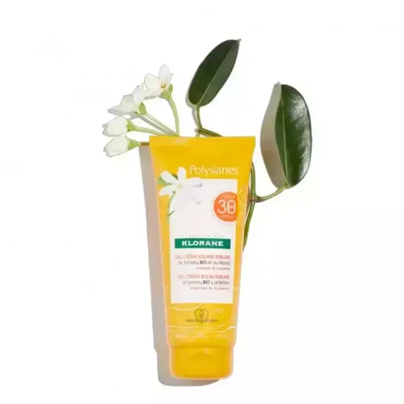 Crème solaire Klorane Polysianes SPF30 sur une plage ensoleillée, océan en fond, évoquant des vacanc