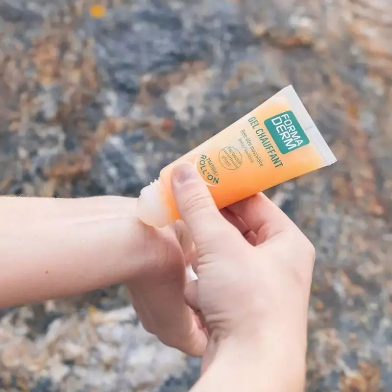 Mains appliquant le roll-on Formaderm Gel Chauffant sur un bras en extérieur, sur une surface en pie