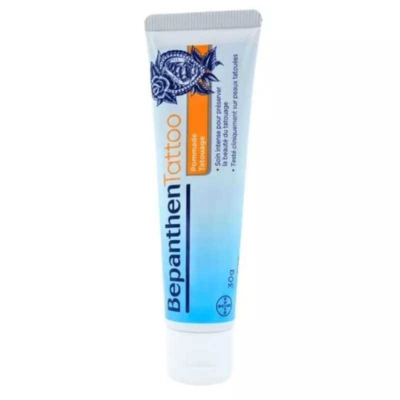 Tube de pommade Bepanthen Tattoo 30 g debout, bouchon blanc et étiquette bleue à motifs de tatouage 