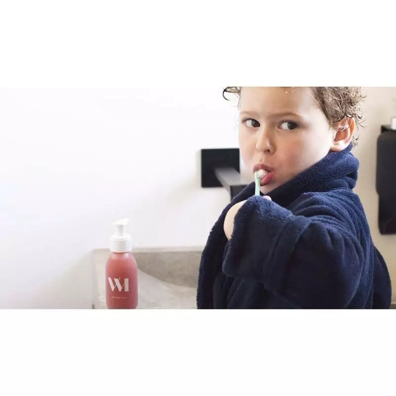 Enfant souriant se brossant les dents avec le dentifrice bio fraise WhatMatters recharge 180ml