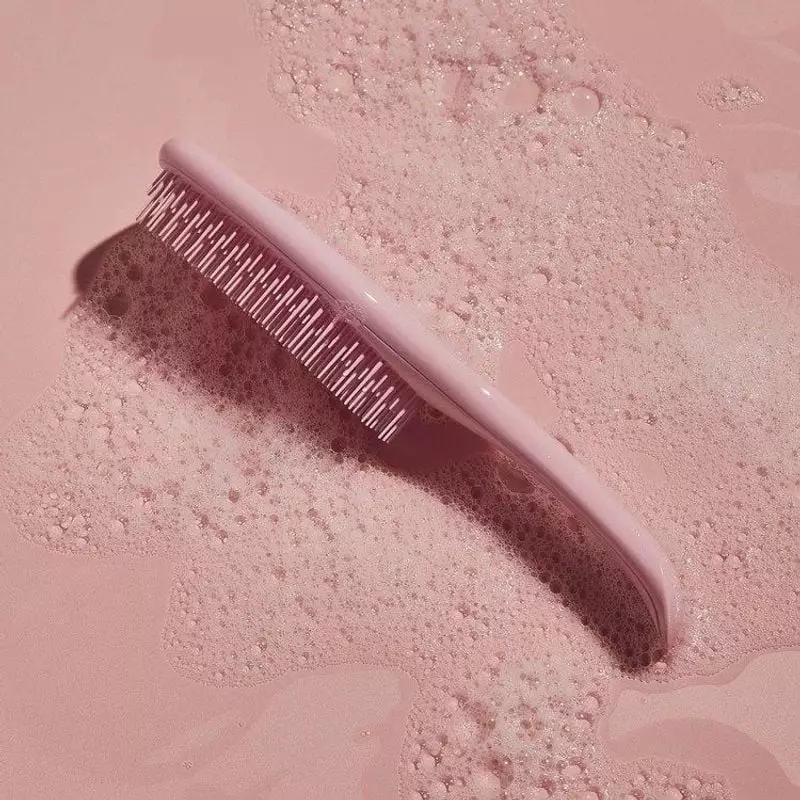 Brosse démêlante Tangle Teezer rose millennial posée sur une eau rose moussante et de la mousse de s