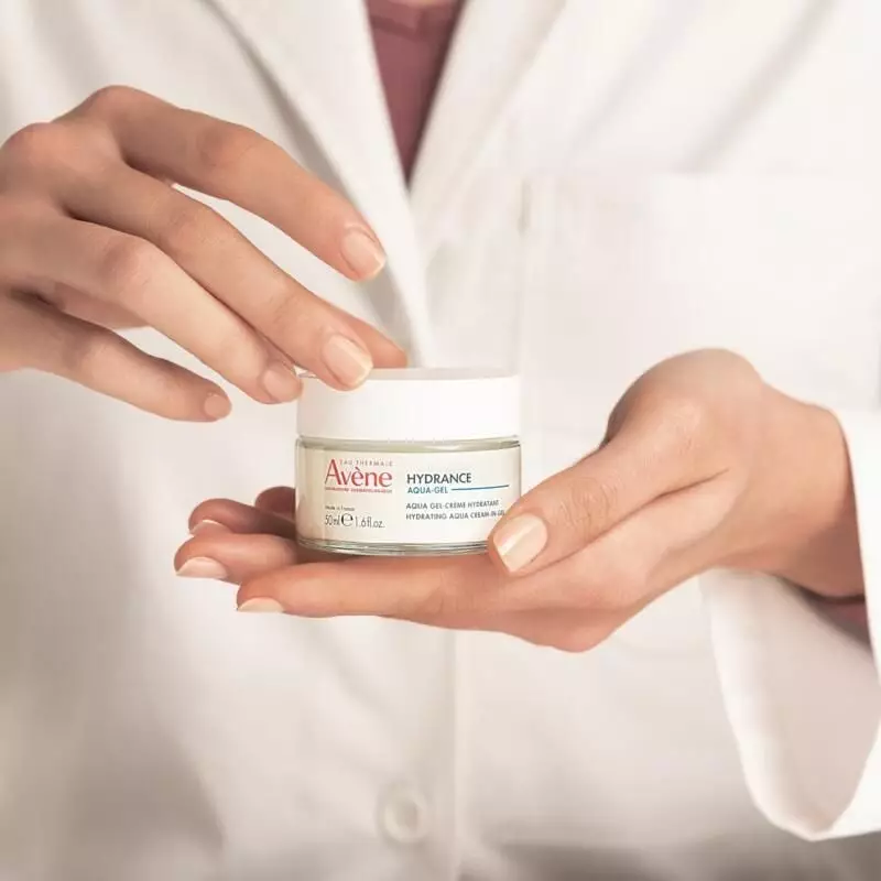 Femme appliquant le gel-crème Avène Hydrance Aqua-Gel hydratant 50 ml sur son visage dans une salle 