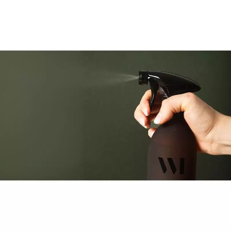 Main appuyant sur la gâchette noire du nettoyant multi-surfaces basilic citron WhatMatters, pulvéris