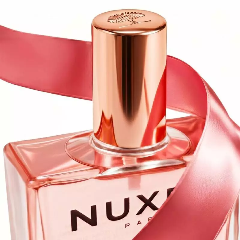 Gros plan sur le bouchon or rose de Nuxe Huile Prodigieuse Florale, gravé d'un motif botanique et or