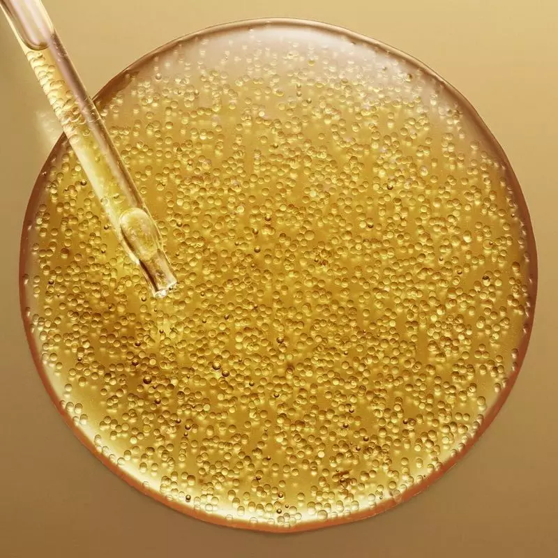 Gros plan sur la texture dorée du Super Sérum Longevity, ses micro-sphères d’huiles botaniques et sa
