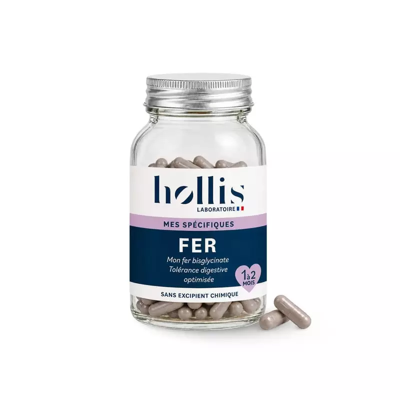 Flacon en verre de complément Hollis Fer, 60 gélules, avec deux gélules beiges à côté sur fond blanc