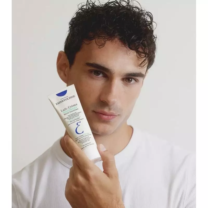 Femme appliquant Embryolisse Lait-Crème Matifiant - 75 ml sur son visage dans une salle de bain lumi
