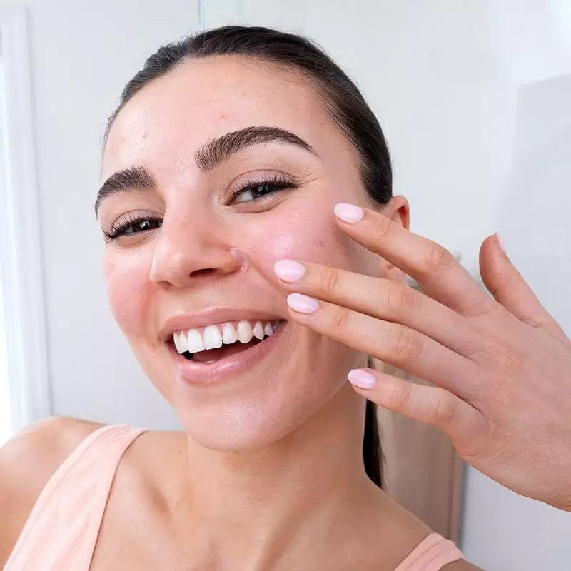 Femme souriante appliquant la pommade réparatrice SVR Cicavit+ 50 g sur la joue et le nez