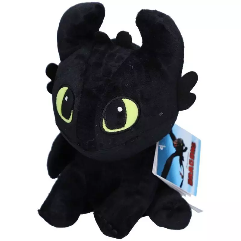Gros plan du visage de la peluche dragon noir aux yeux verts brodés et étiquette DreamWorks Dragons